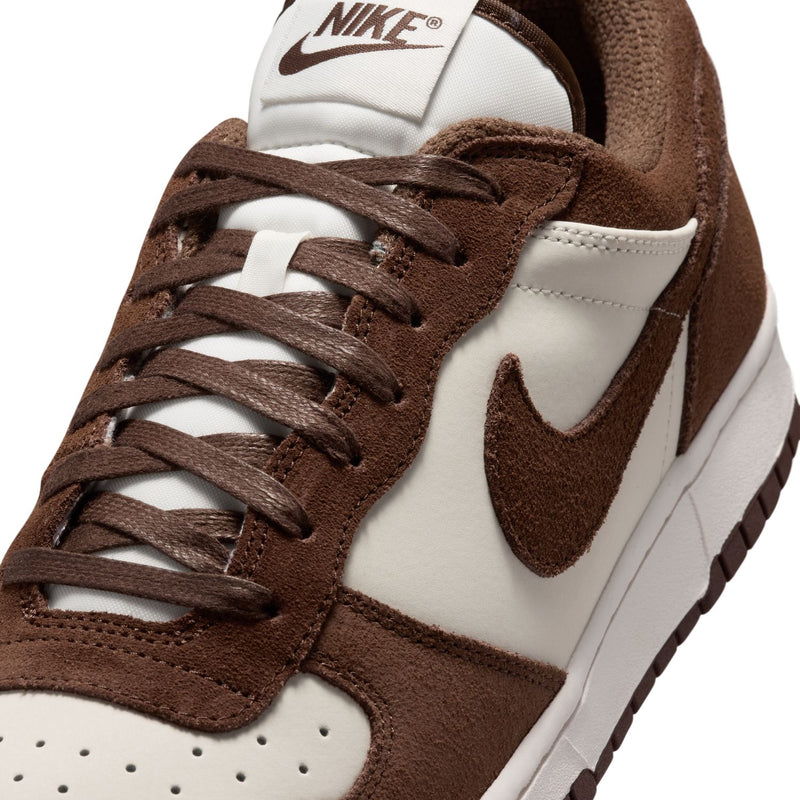 Close-up of men's low-top Nike sneakers: brown suede upper, white panels, and lace-up rows
