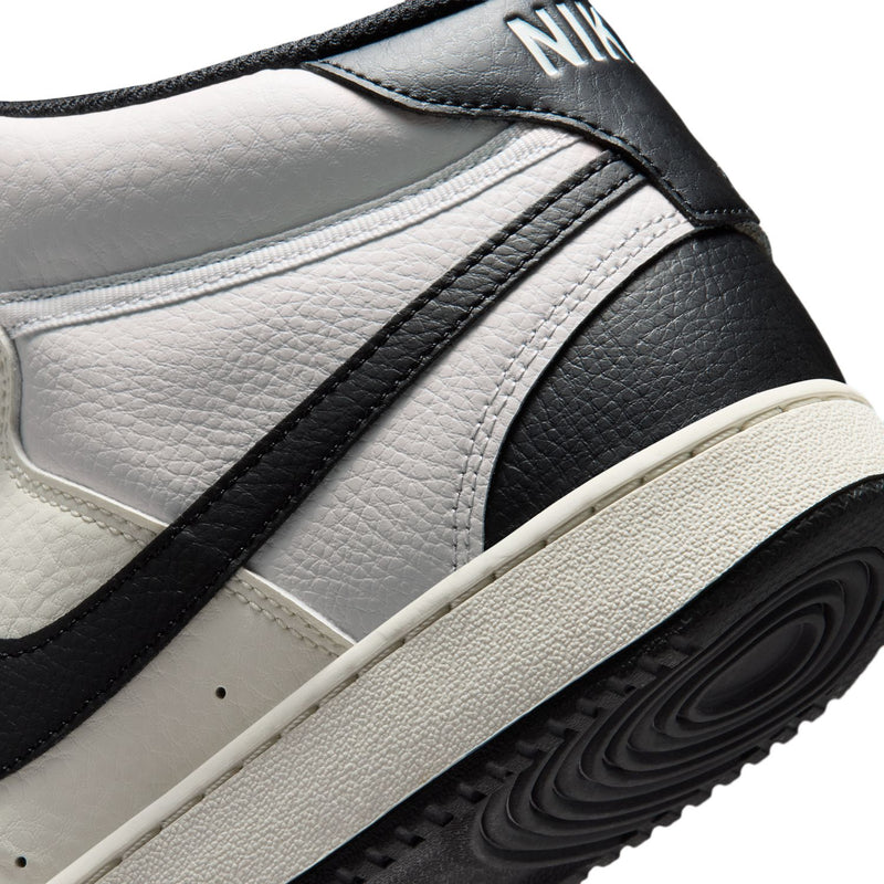 Men's sneaker upper close-up: textured off-white and black panels with rubber sole.