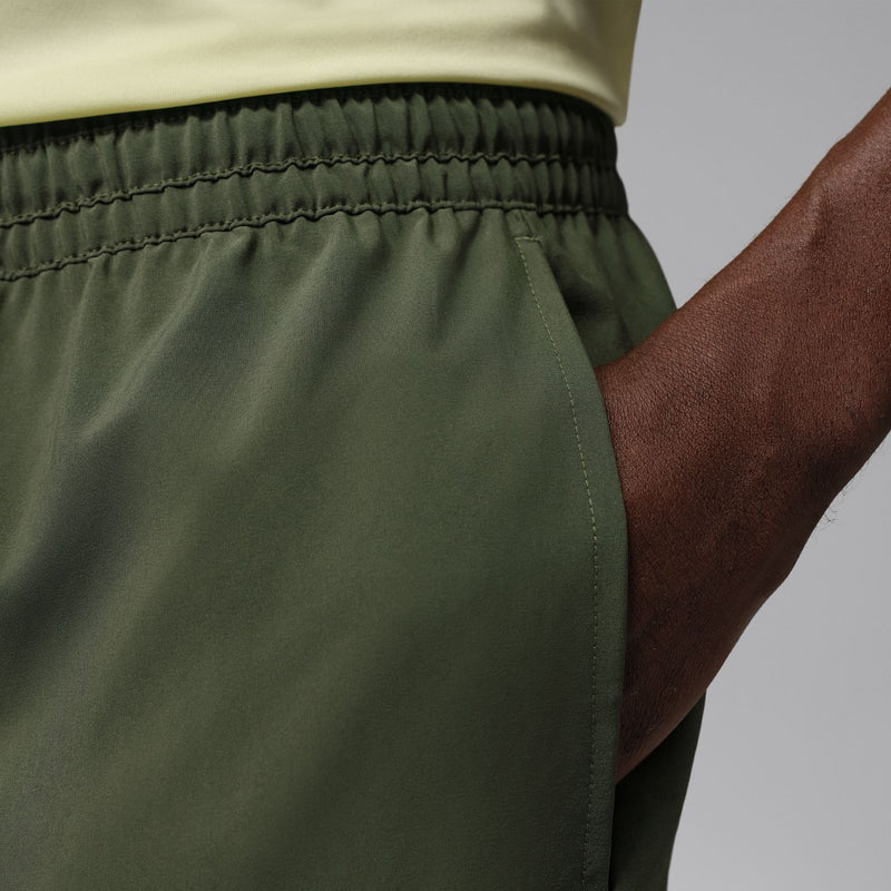 Close-up of olive woven shorts waist seam with elastic and drawstring channel