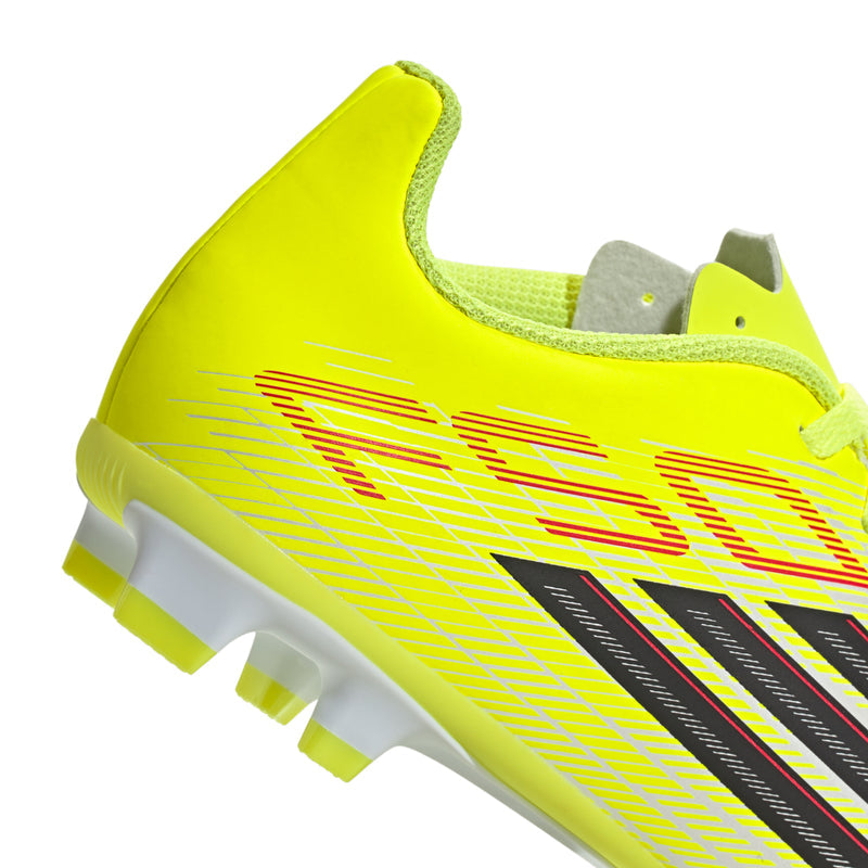 Youth soccer cleat side close-up, neon yellow upper with black stripes and red accents