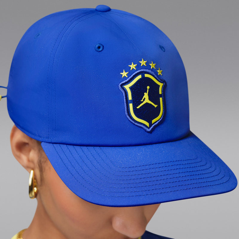 Royal blue snapback cap with yellow Jordan shield logo, angled side view