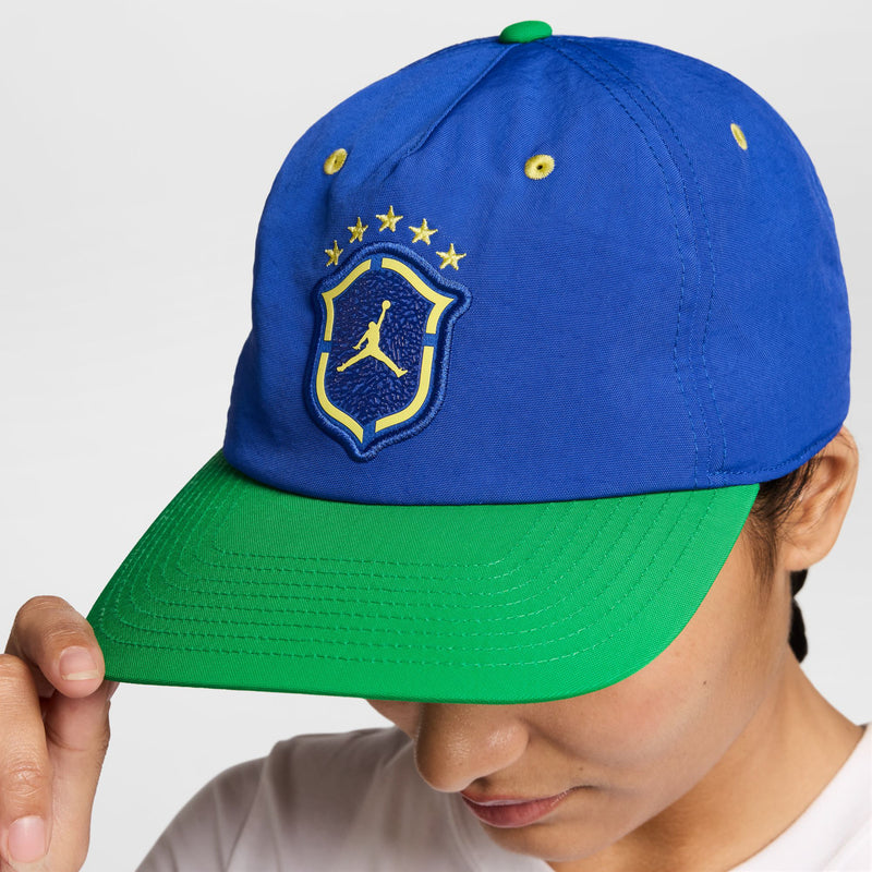 Royal blue snapback cap with yellow Jordan shield logo and green brim underside