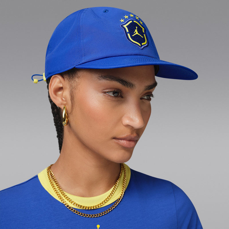 Royal blue snapback cap with yellow Jordan shield logo, worn at an angle