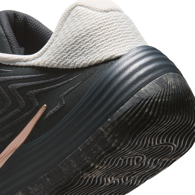 Men's low-top shoe close-up: black midsole with rose-gold logo and textured tread