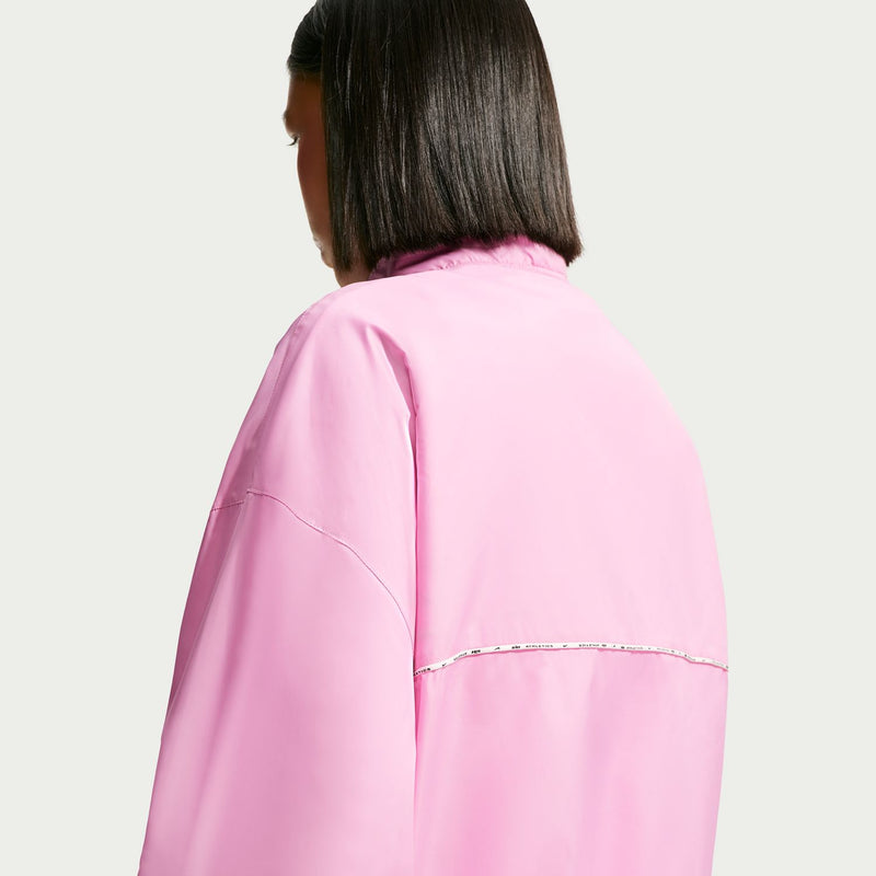 Women's pink windbreaker jacket back view with reflective seam piping across shoulders