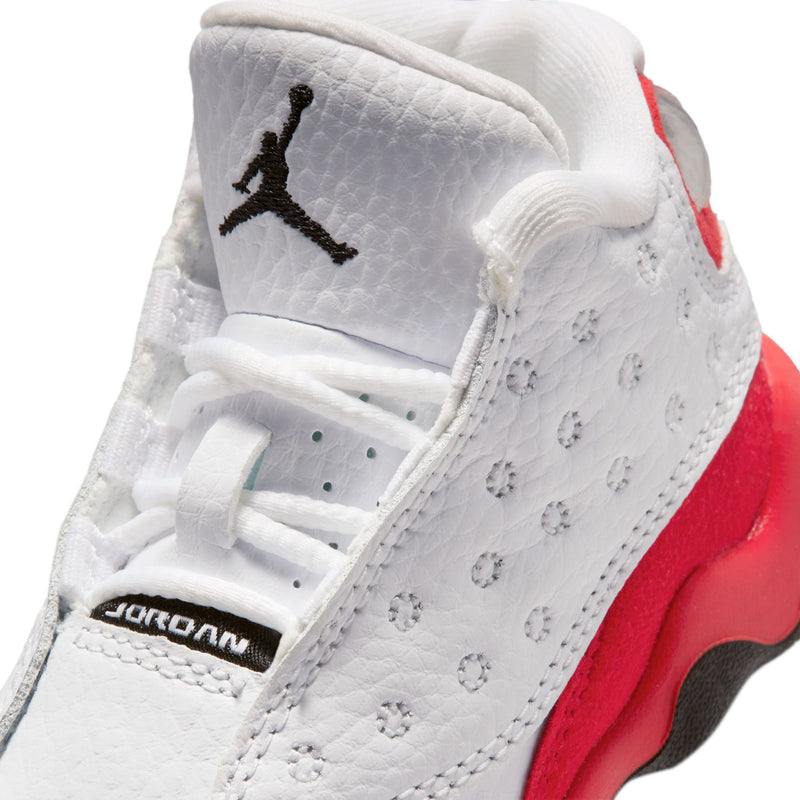 Toddler sneaker close-up with Jordan logo, white leather, red midsole, and black accents.
