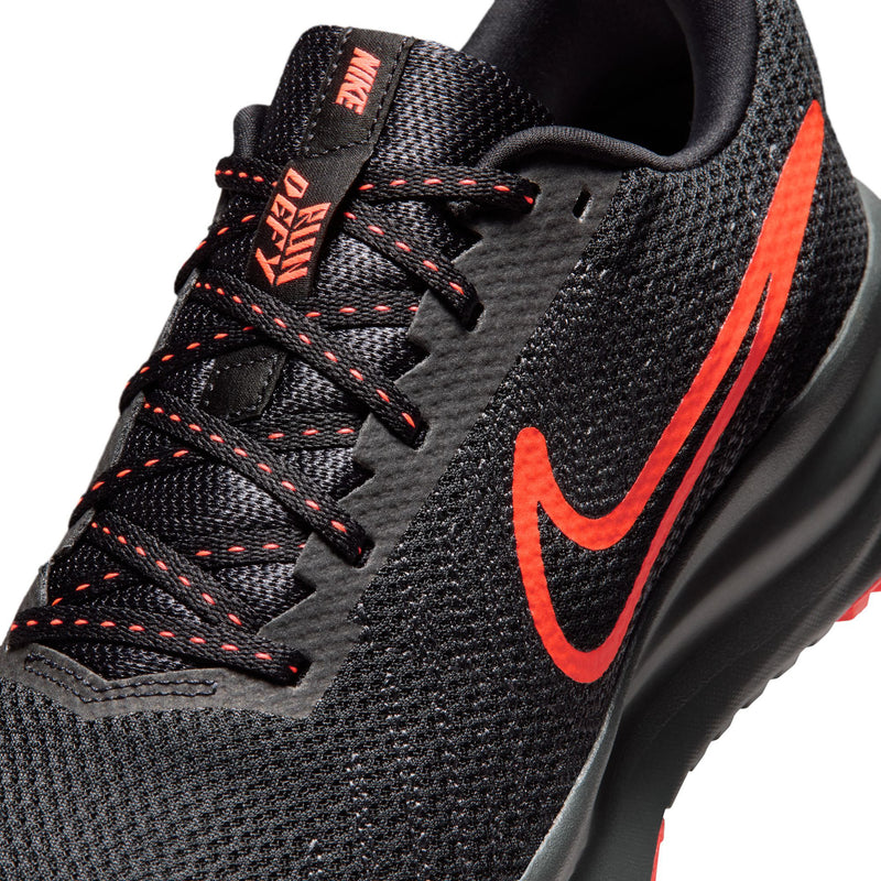Men's black running shoe close-up with crimson laces, Swoosh, and textured knit