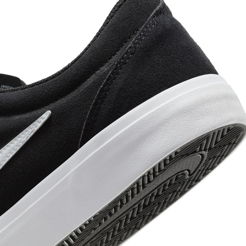 Men's black suede skate sneaker side close-up with white midsole and textured outsole.