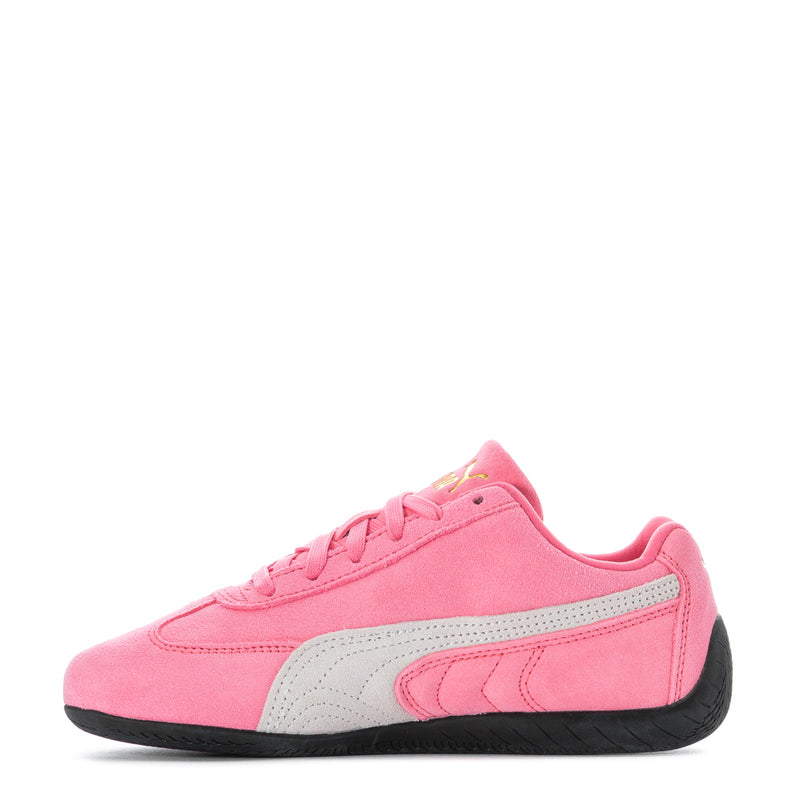 Pink youth Puma sneakers with white side stripe, black outsole, and lace-up front.