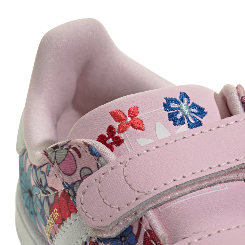 Toddler sneaker close-up: pink stitched strap with small blue and red floral details.