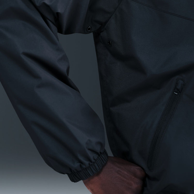 Men's black windbreaker fabric close-up with front zipper, snap placket, and side pocket
